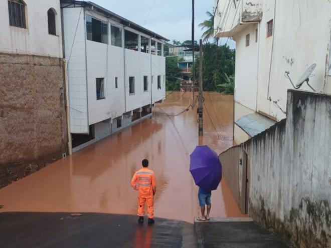 Bombeiros monitoram situação de córrego que transbordou, inundou repentinamente rua em Naque e deixou isolados moradores de dois prédios