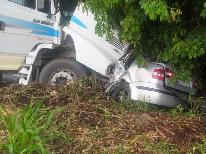 Com o impacto, caminhão arrastou o veículo por vários metros até parar no meio do mato; Caminhoneiro disse que se deparou com VW Polo sem controle e invadindo a contramão de direção 