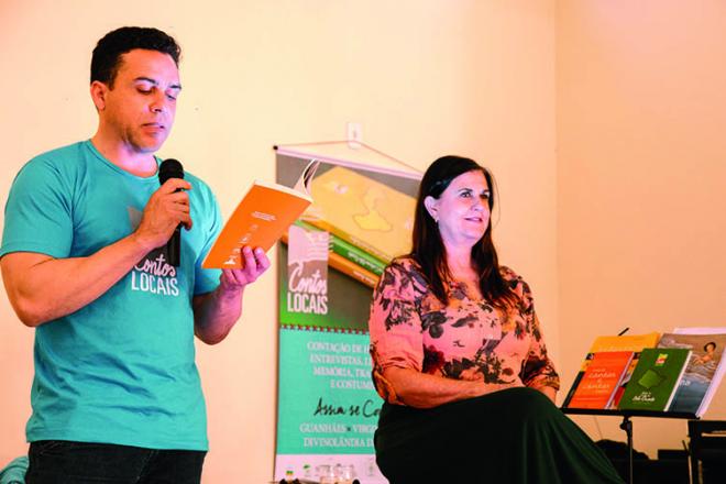 Cristiano Lopes lê uma história, observado por Bia Bedran