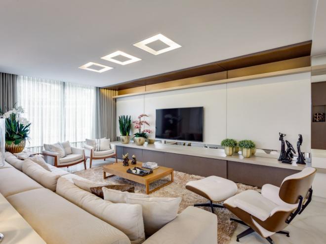 Conforto e design: Nesse espaço projetado pelo escritório Machado, Weiss e Moraes Arquitetura e Interiores, a escolha de nuances neutras trouxe um ar bastante aconchegante à sala de TV. O grande destaque do ambiente fica por conta da poltrona Lounge Eames, que além de confortável, é uma obra de arte que carrega parte da história do design do século XX